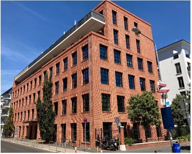 Außenansicht eines mehrstöckigen roten Backsteingebäudes, dem Standort der Trinity Management Systems GmbH in Frankfurt am Main.